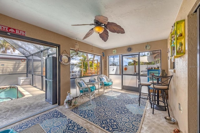 sunroom / solarium featuring a ceiling fan