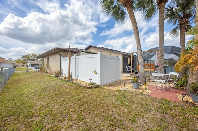 view of yard featuring a patio, a fenced backyard, and glass enclosure