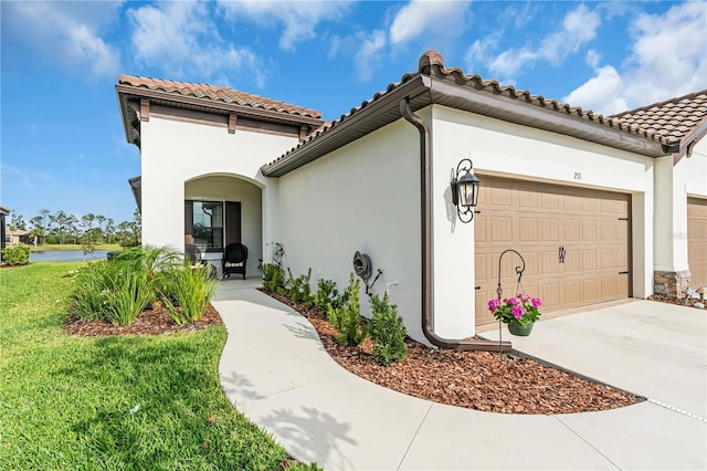 view of front of house with driveway, an attached garage, a tiled roof, and stucco siding