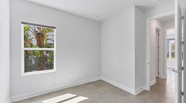 tiled empty room featuring baseboards