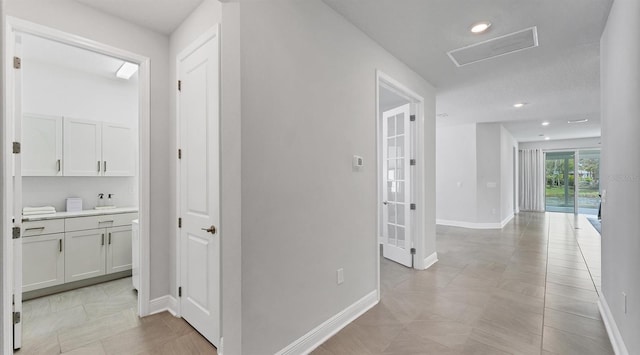 hallway with recessed lighting, baseboards, and a sink