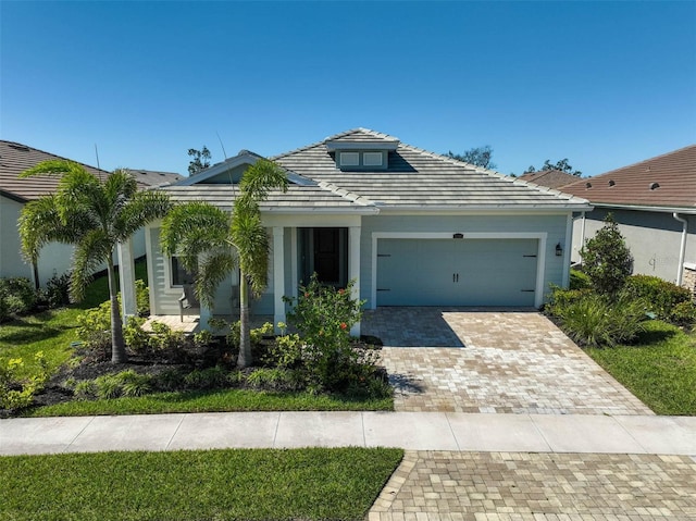 view of front facade with a tile roof, decorative driveway, and a garage