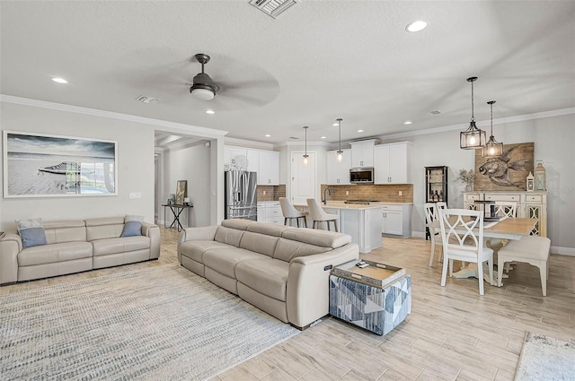 living room featuring visible vents, a textured ceiling, crown molding, and ceiling fan