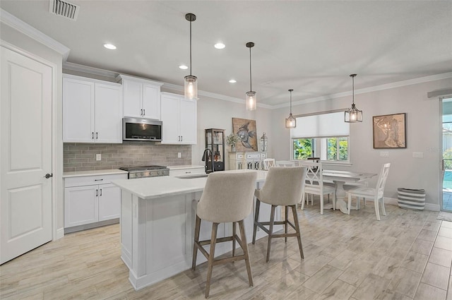 kitchen with visible vents, a sink, light countertops, stainless steel microwave, and range