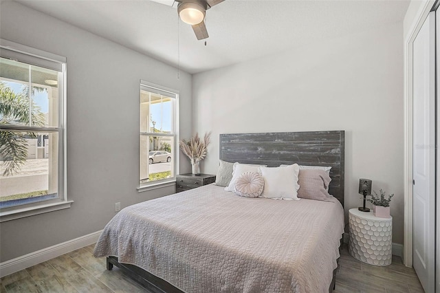 bedroom with multiple windows, baseboards, and wood finished floors