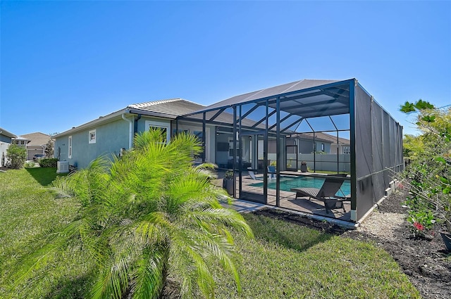 rear view of house with a lanai, stucco siding, an outdoor pool, and a yard