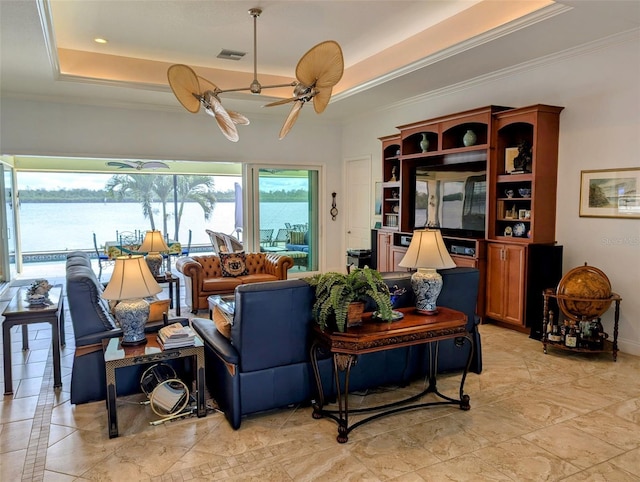 living area featuring visible vents, a ceiling fan, ornamental molding, a water view, and a tray ceiling