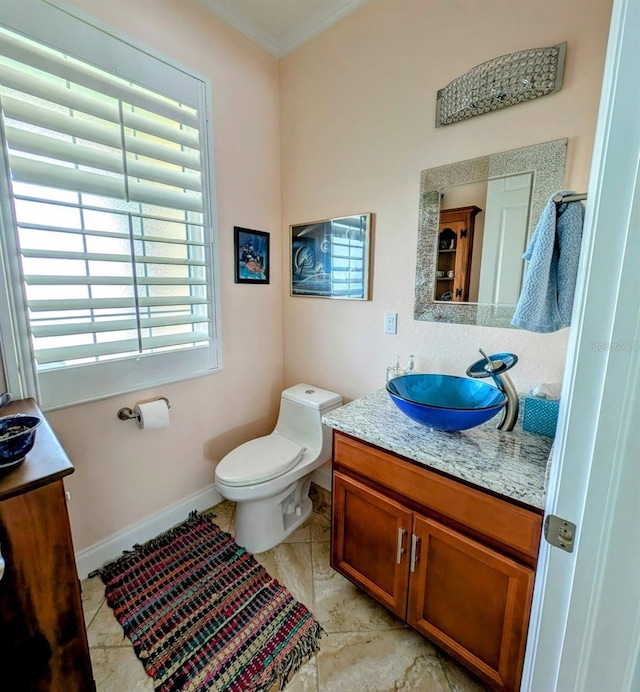 bathroom featuring tile patterned flooring, toilet, vanity, baseboards, and ornamental molding