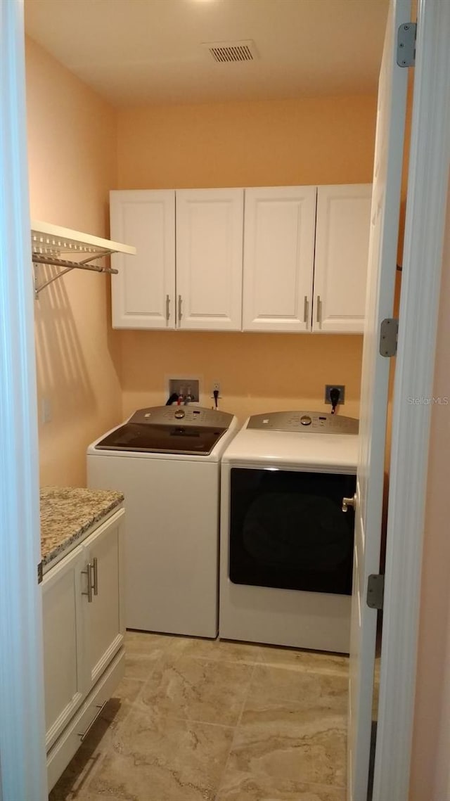 laundry area with visible vents, washing machine and dryer, and cabinet space