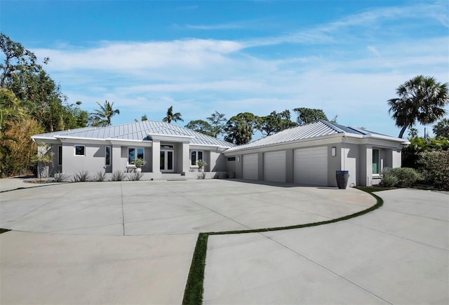 view of front of house featuring driveway, a standing seam roof, metal roof, and stucco siding