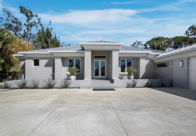 back of property with metal roof, french doors, a standing seam roof, and stucco siding