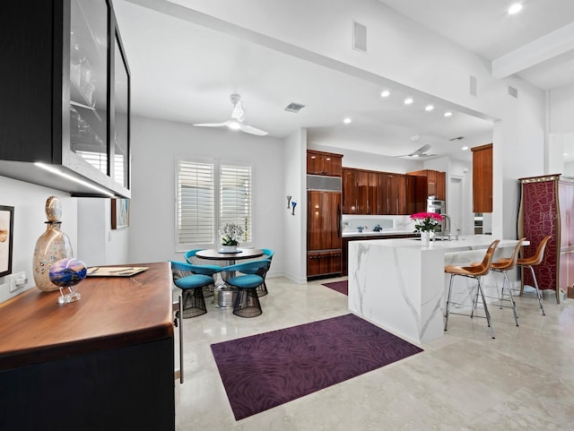 kitchen with a ceiling fan, visible vents, built in refrigerator, and a kitchen bar