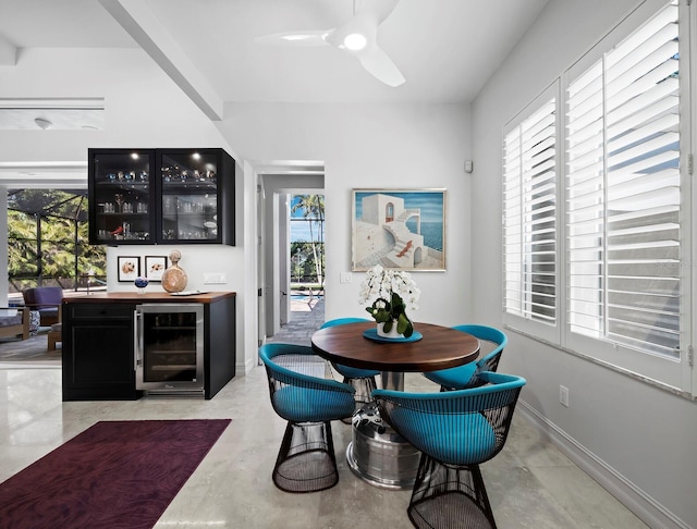 bar with beverage cooler, a bar, plenty of natural light, and baseboards