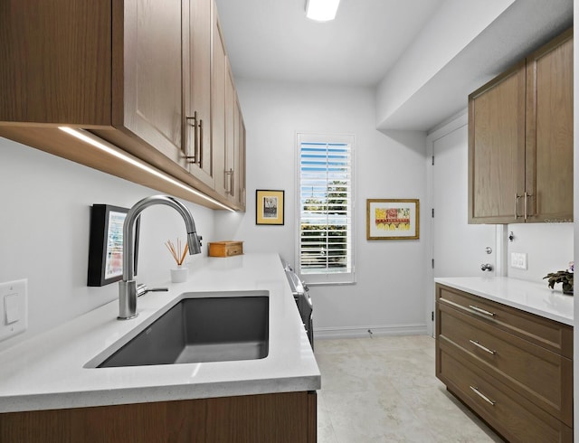 kitchen with baseboards, light countertops, and a sink