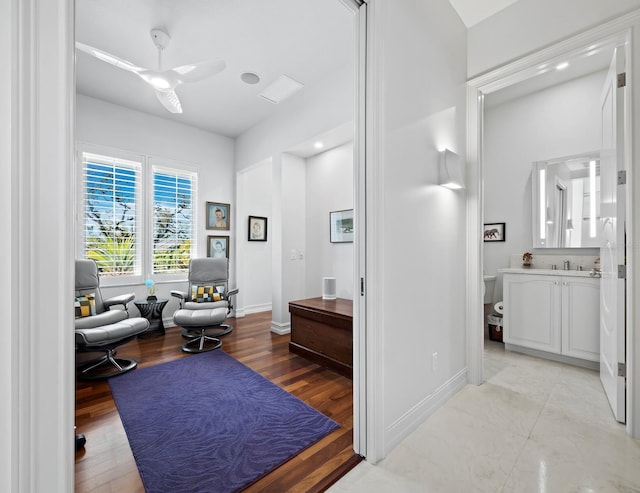 interior space with ceiling fan, baseboards, wood finished floors, and vanity