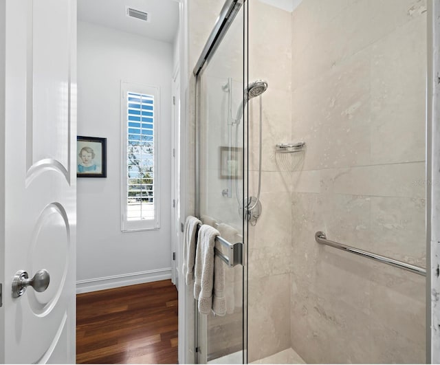 full bath with a stall shower, wood finished floors, visible vents, and baseboards