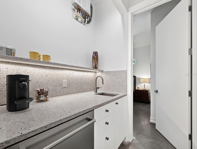 kitchen with light stone countertops, a sink, white cabinets, decorative backsplash, and dishwasher