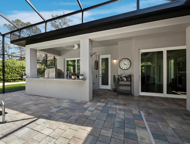 view of patio with a lanai, a sink, and area for grilling