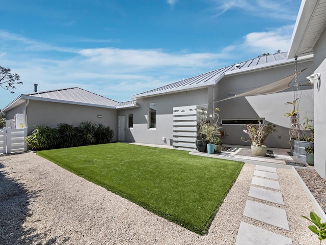 exterior space featuring a standing seam roof, a yard, metal roof, and stucco siding