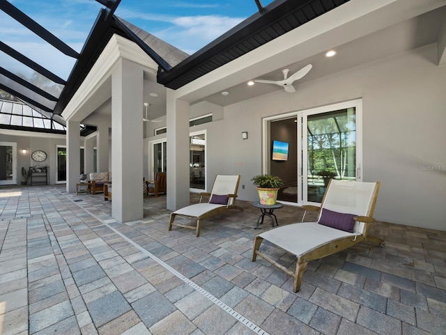 view of patio / terrace featuring a ceiling fan and glass enclosure