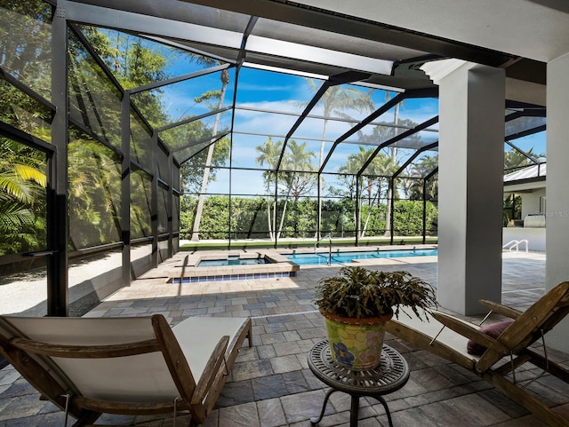 view of pool featuring glass enclosure, a pool with connected hot tub, and a patio