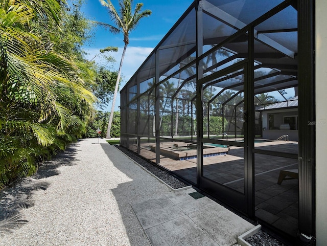 exterior space with glass enclosure, a jacuzzi, and an outdoor pool