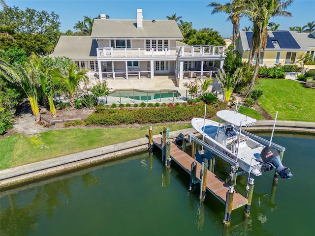 rear view of property with a patio, a balcony, an outdoor pool, a water view, and boat lift