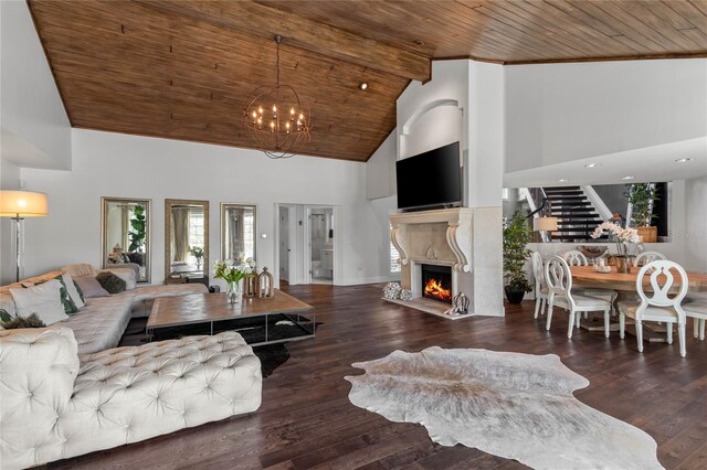 living room featuring high vaulted ceiling, a warm lit fireplace, wood finished floors, stairway, and wooden ceiling