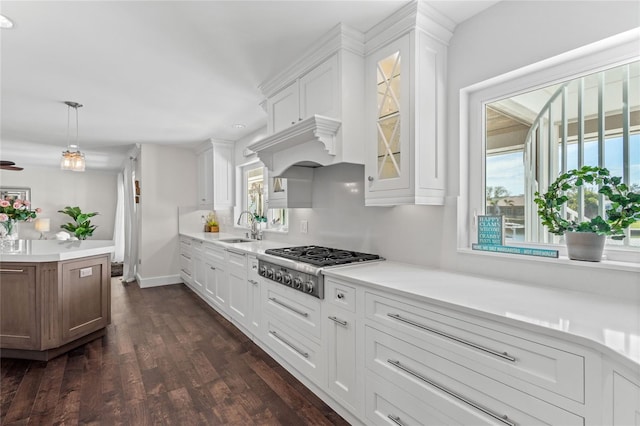 kitchen with dark wood-type flooring, a sink, white cabinetry, stainless steel gas stovetop, and light countertops