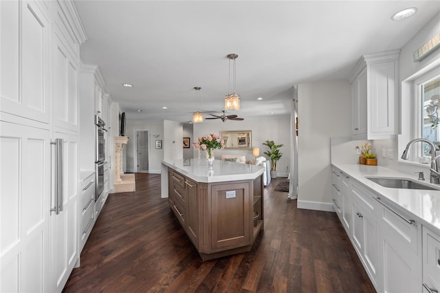 kitchen featuring white cabinets, a center island, light countertops, and a sink