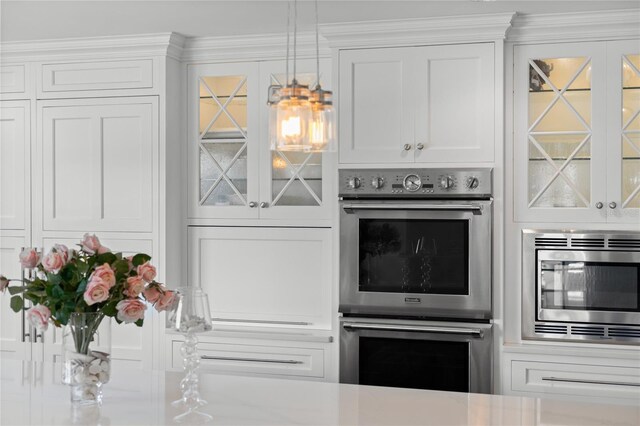 kitchen featuring decorative light fixtures, stainless steel appliances, glass insert cabinets, and white cabinetry