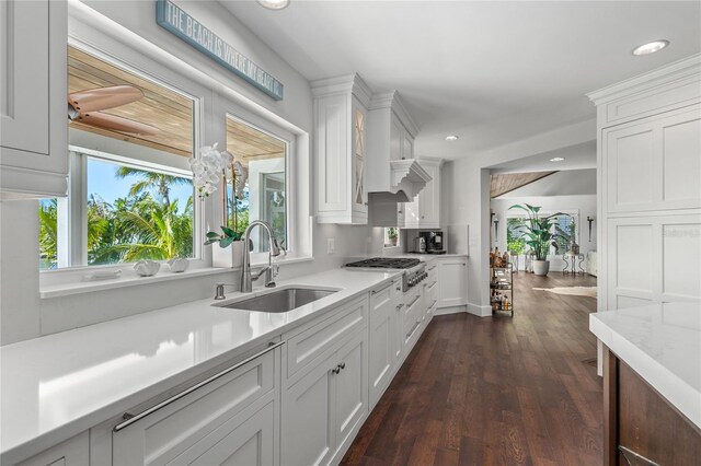 kitchen with dark wood-type flooring, light countertops, recessed lighting, white cabinetry, and a sink