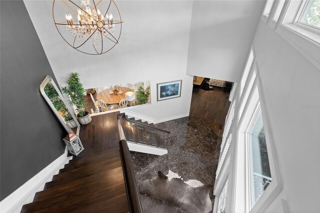 stairway with an inviting chandelier and baseboards