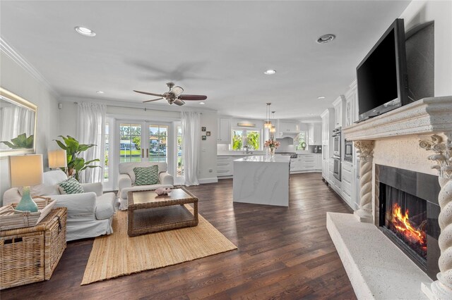 living room featuring a ceiling fan, recessed lighting, a fireplace, dark wood-style flooring, and crown molding