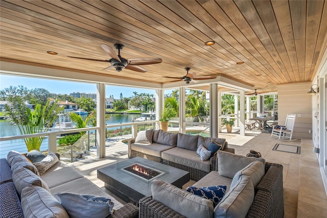 view of patio with an outdoor living space with a fire pit, a ceiling fan, and a water view