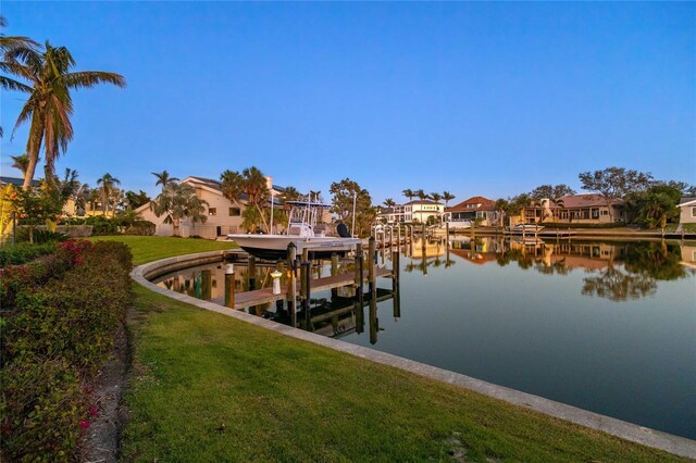 dock area with boat lift, a lawn, a residential view, and a water view