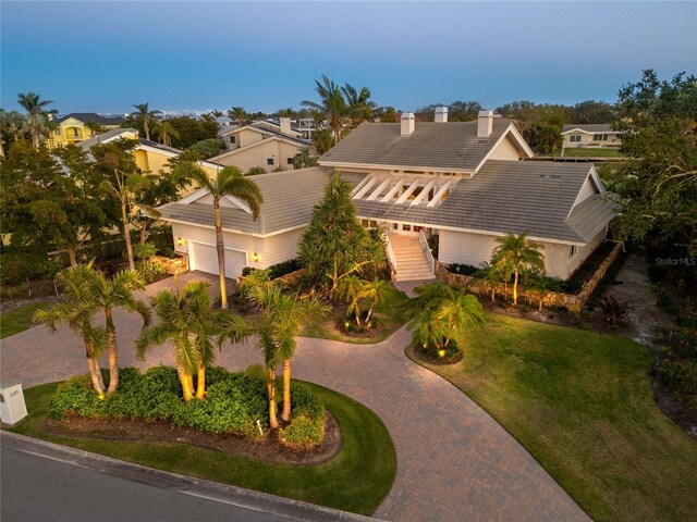 view of front of house featuring stairway, an attached garage, a front lawn, a tiled roof, and decorative driveway