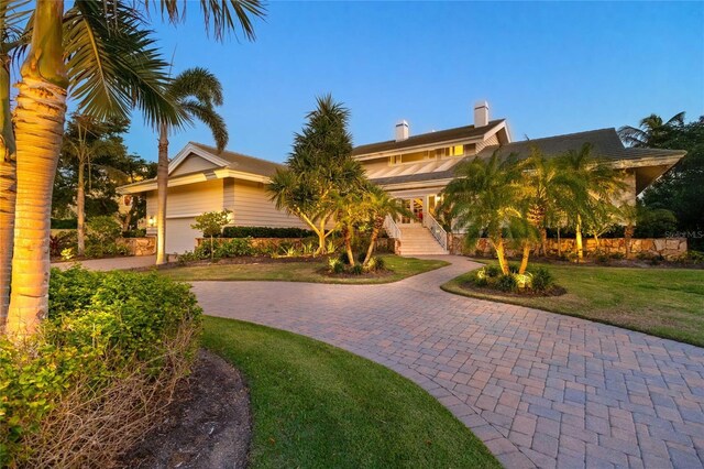 view of front of property featuring a front lawn, decorative driveway, and a chimney