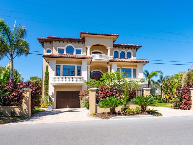 mediterranean / spanish-style home featuring stucco siding, a tile roof, decorative driveway, and a balcony