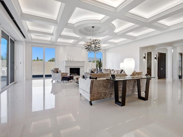 living room featuring ornate columns, a notable chandelier, a fireplace, and coffered ceiling