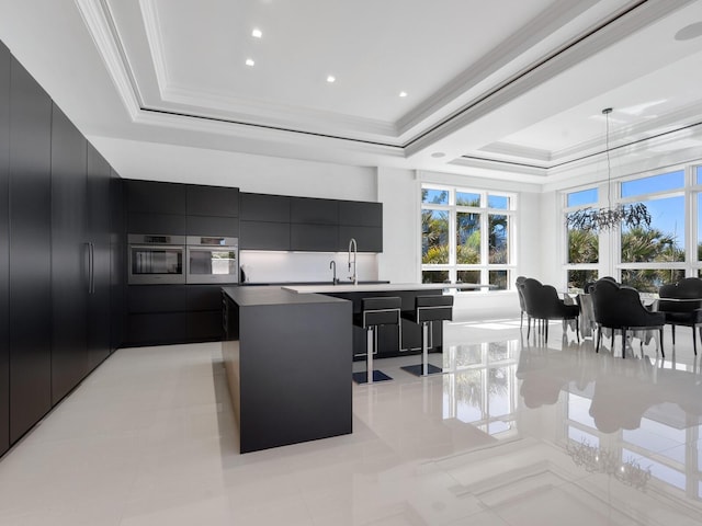 kitchen featuring a tray ceiling, a sink, crown molding, modern cabinets, and dark cabinets