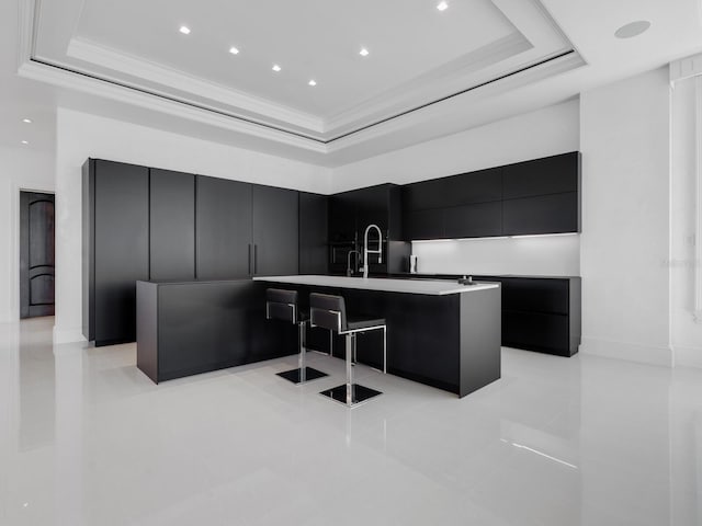 kitchen featuring dark cabinetry, a tray ceiling, ornamental molding, light countertops, and modern cabinets