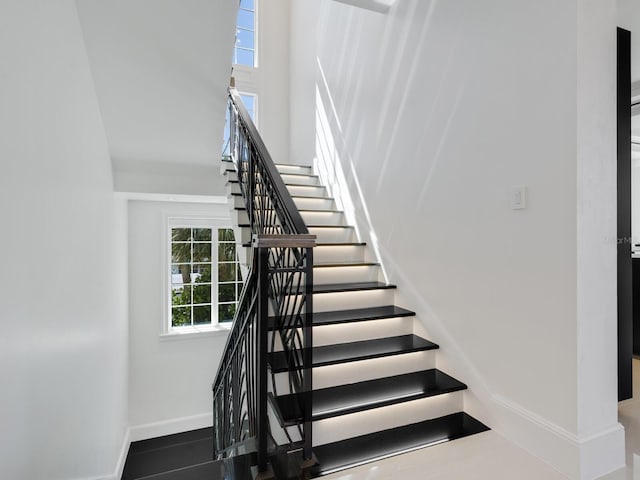 stairway with baseboards and a towering ceiling