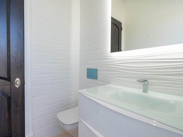 bathroom with toilet, tile walls, and vanity