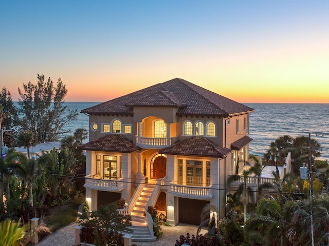 view of front of property featuring a balcony, stairway, a water view, and stucco siding