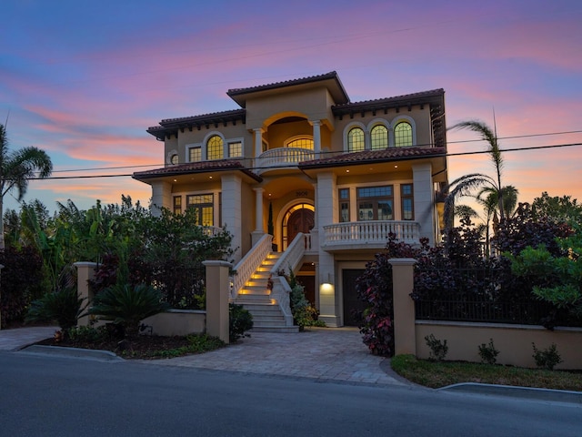 mediterranean / spanish-style home featuring decorative driveway, stairway, an attached garage, a balcony, and a tiled roof