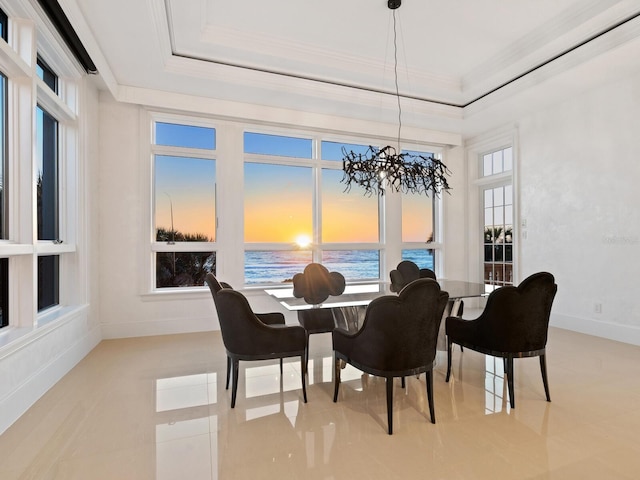 dining area with a water view, a tray ceiling, crown molding, baseboards, and a chandelier