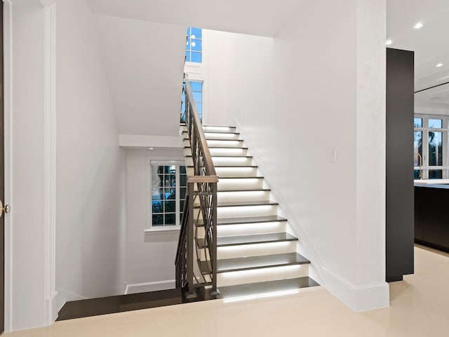 stairway featuring recessed lighting, baseboards, and a towering ceiling