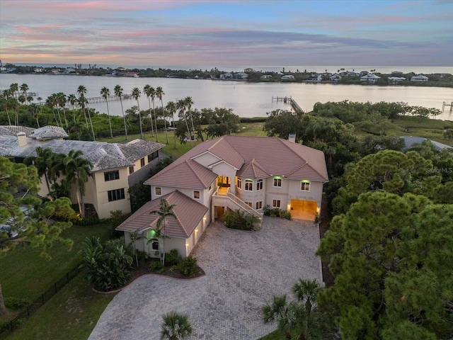 aerial view at dusk featuring a water view