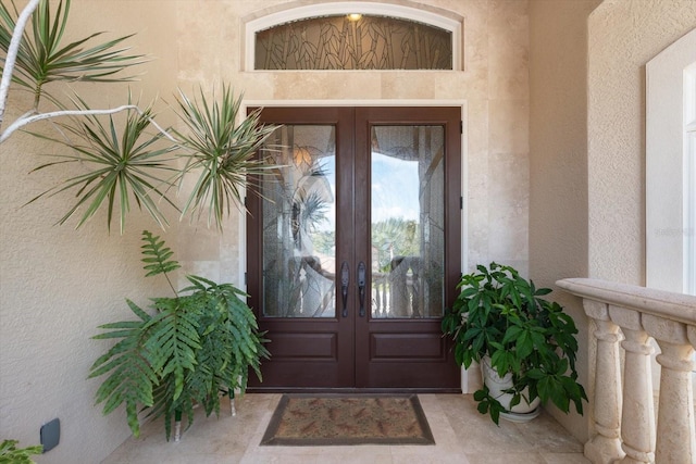 view of exterior entry featuring stucco siding and french doors